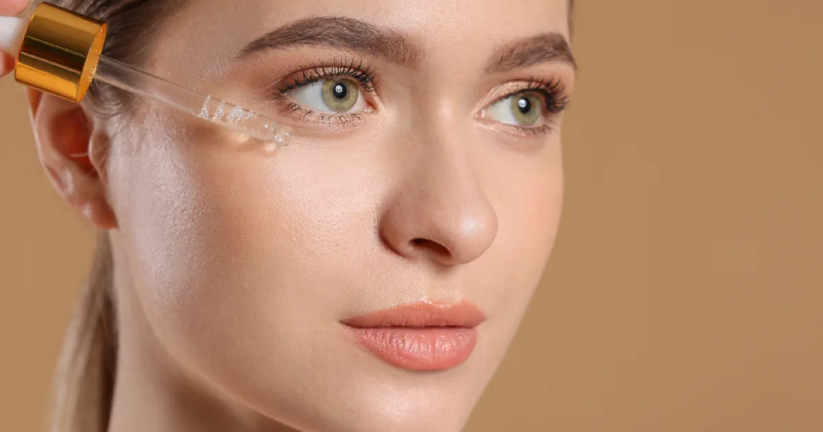 Gros plan du visage d'une femme, application d'un soin au compte-gouttes près de l'œil
