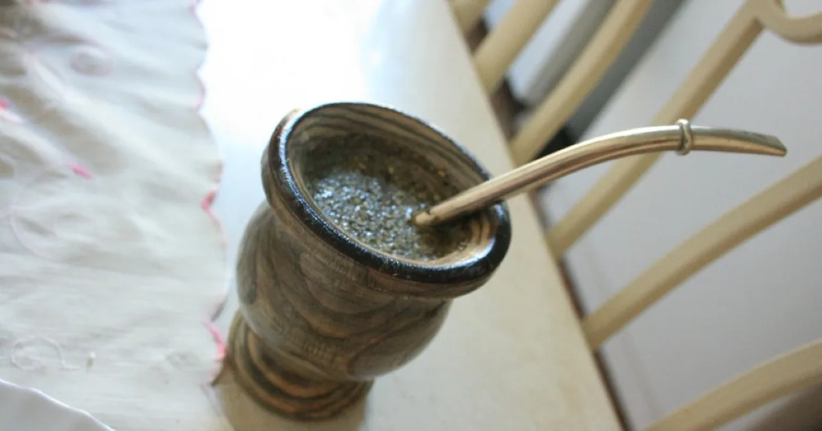 Calebasse de maté traditionnelle avec bombilla en métal posée sur une table en bois