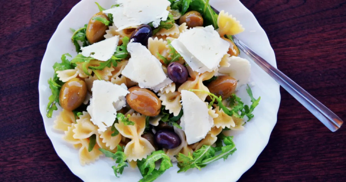 Assiette de salade de pâtes méditerranéenne aux olives, roquette et copeaux de fromage